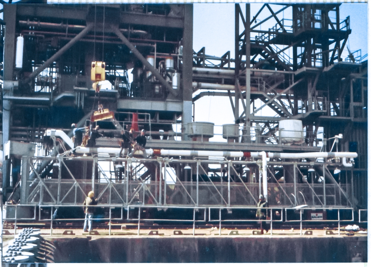 Union Ironworkers from Local 808 working for Ivey Steel at Space Shuttle Launch Complex 39-B, Kennedy Space Center, Florida, ride herd on the lifting gear which has been attached to the Gaseous Oxygen Vent Arm Main Truss, as the crane operator comes up on his load very slowly, making sure all of the rigging is properly aligned prior to coming into tension, immediately afterwhich the 65-foot long truss will be lifted into place nearly 250 feet directly above where this work is ongoing, where it will be attached to the Fixed Service Structure.